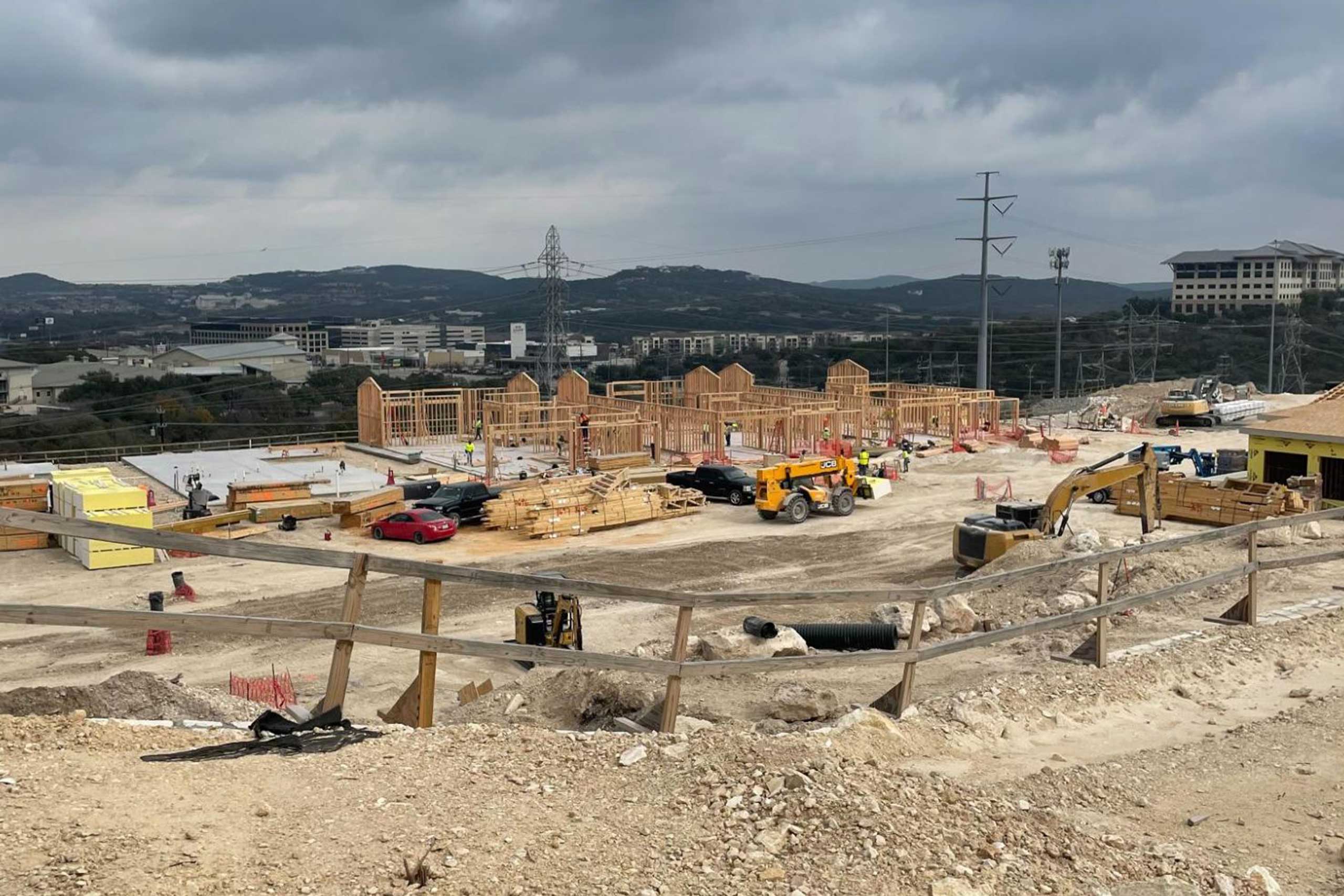 Bella Vida construction site with crews working on site walls, utilities, concrete slabs, and new framing at the Memory Care building, Phase 3 villas, and quadplex foundations.