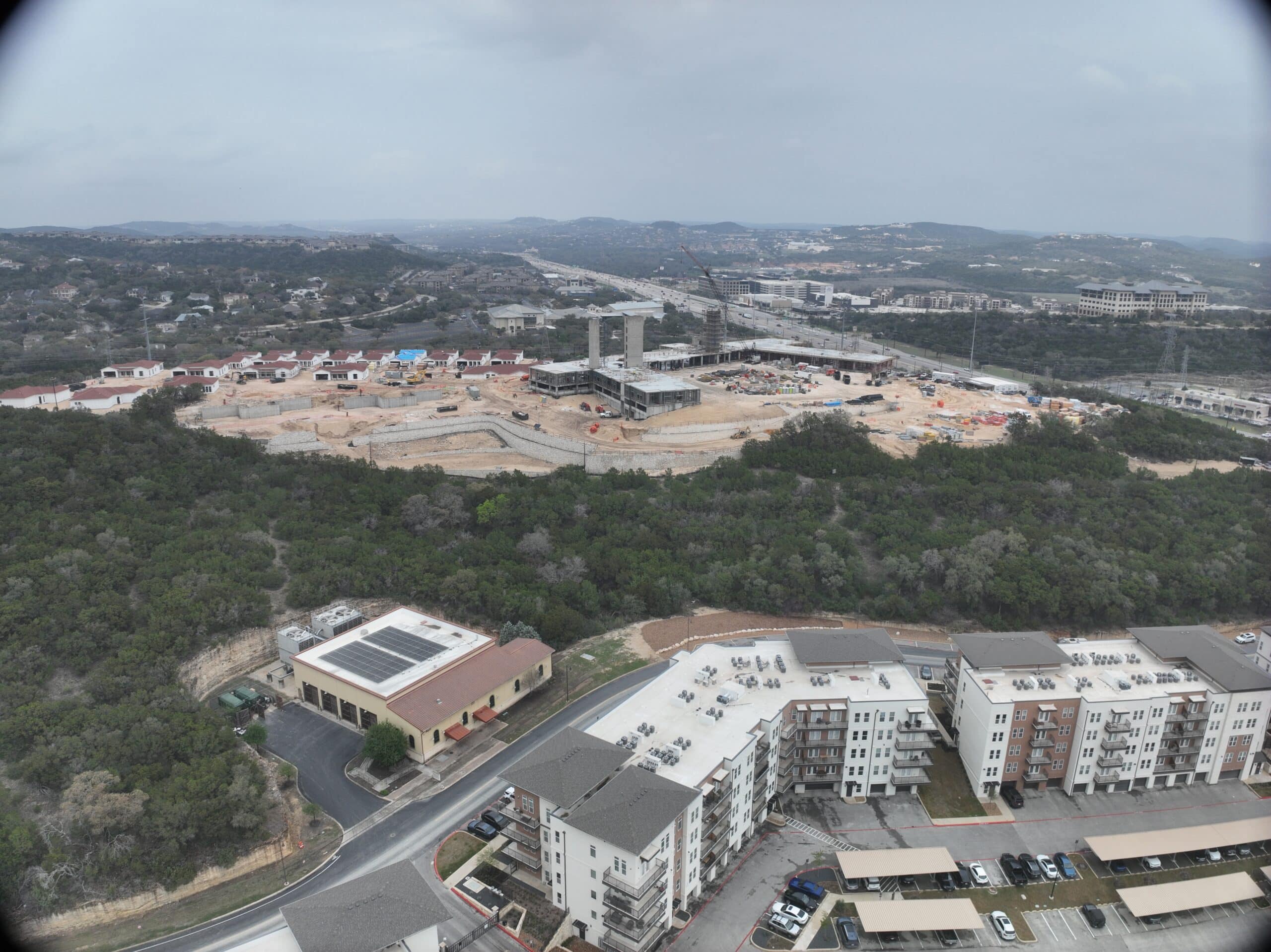 Bella Vida construction site with crews working on site walls, utilities, concrete slabs, and new framing at the Memory Care building, Phase 3 villas, and quadplex foundations.