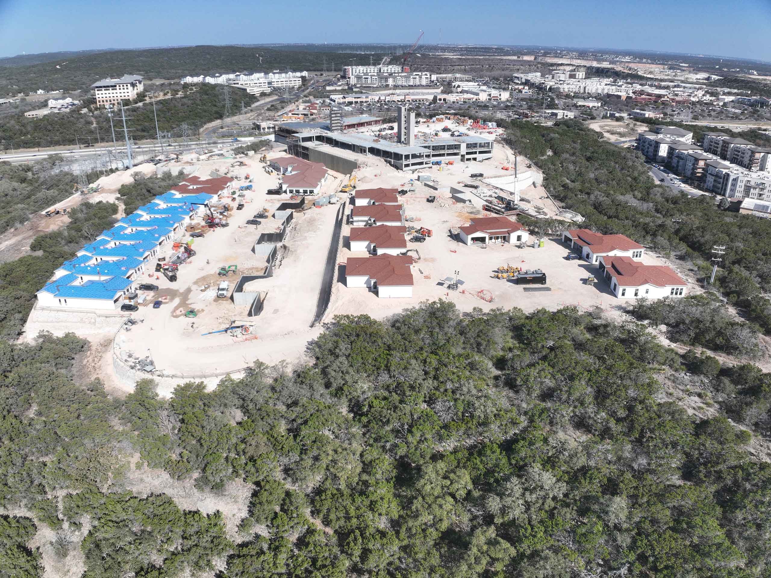 Bella Vida construction site with crews working on site walls, utilities, concrete slabs, and new framing at the Memory Care building, Phase 3 villas, and quadplex foundations.